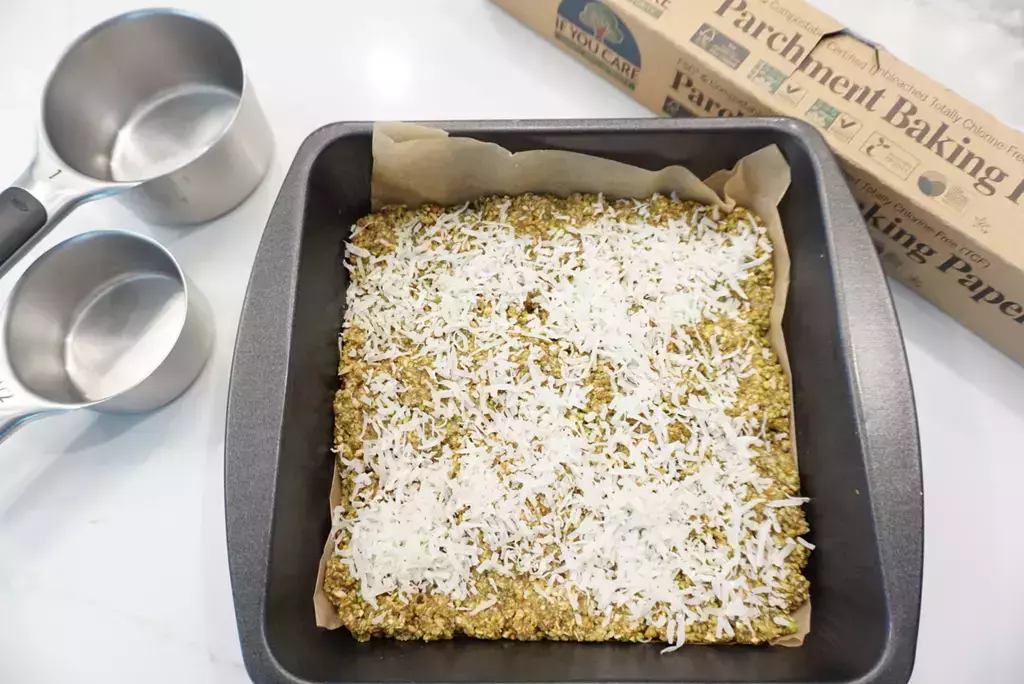 pistachio snack squares in pan with coconut flakes